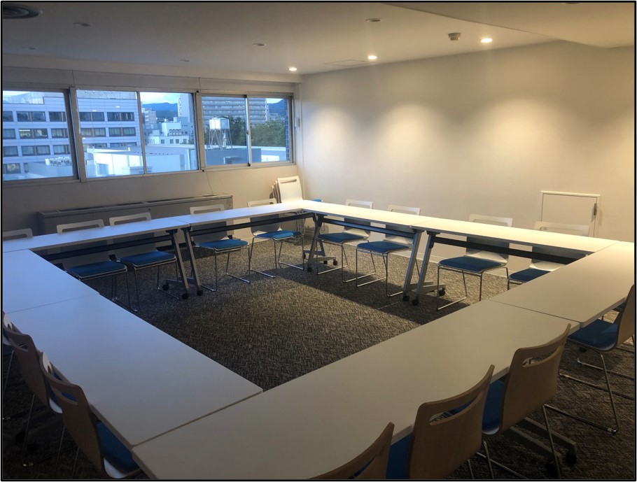 ロの字型に長机が並んでいる。16脚の椅子がある。